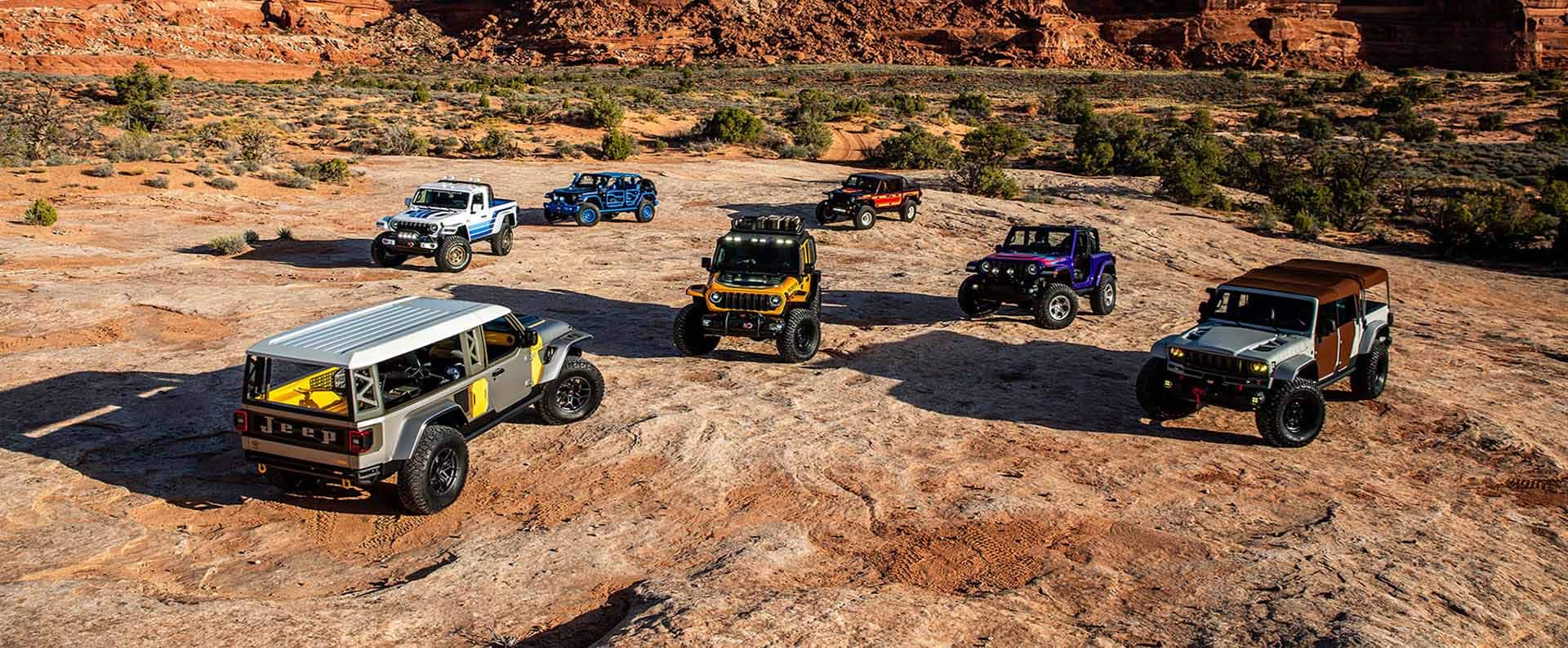 A group of seven Jeep Concept vehicles parked on a clearing in the desert.