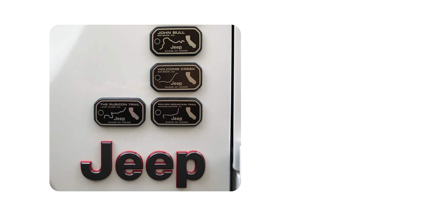 The Jeep badge on the exterior of a Jeep Brand vehicle, along with four Jeep Badge of Honor badges.